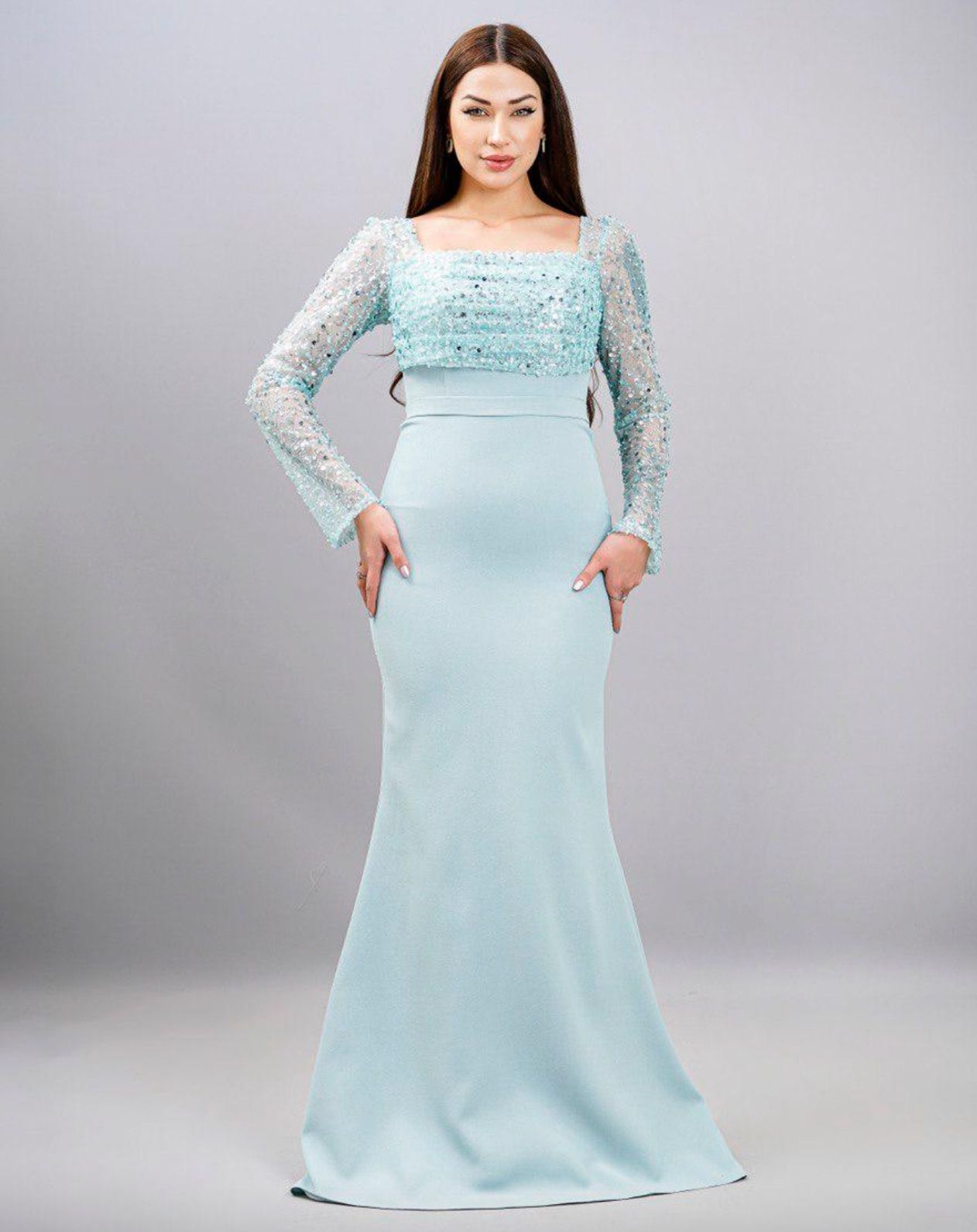 Woman in a light blue formal gown with long sleeves, standing in a studio β Nur's Collection In Rockdale, NSW