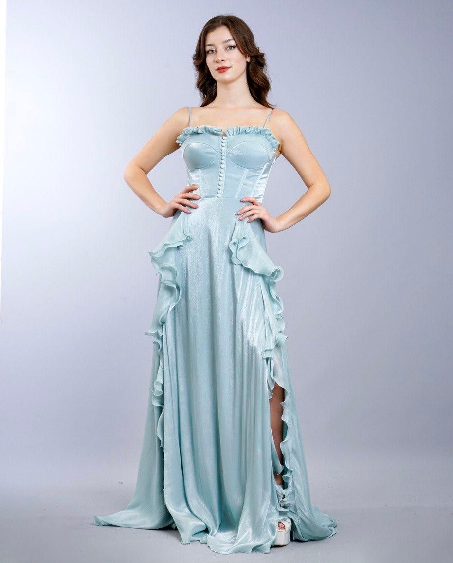 Woman in a light blue, ruffled gown with a high slit, posing with hands on hips β Nur's Collection In Rockdale, NSW
