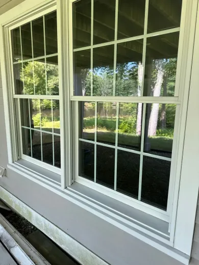There are two windows on the side of a house.