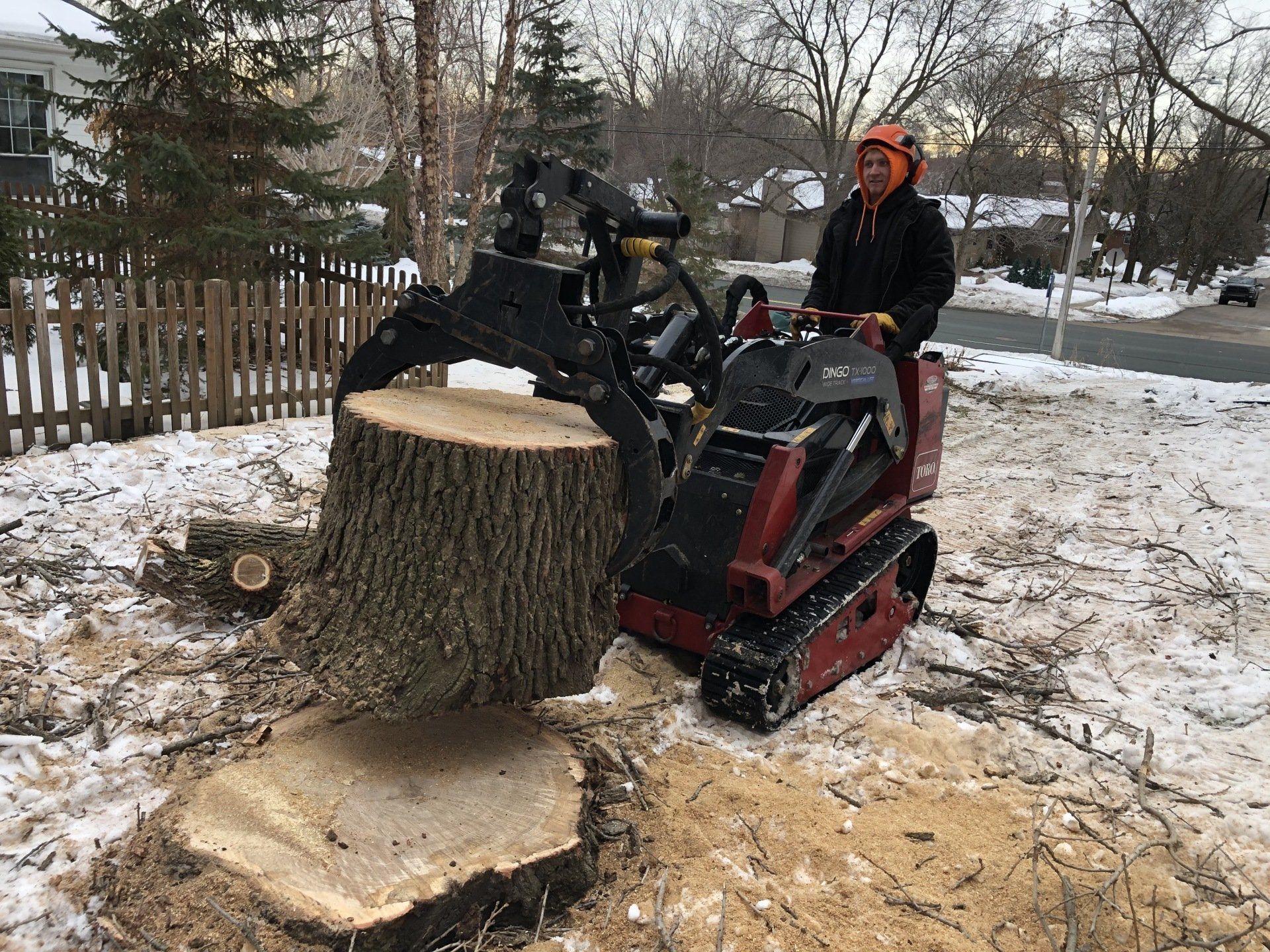 A man is using a machine to remove a tree stump.