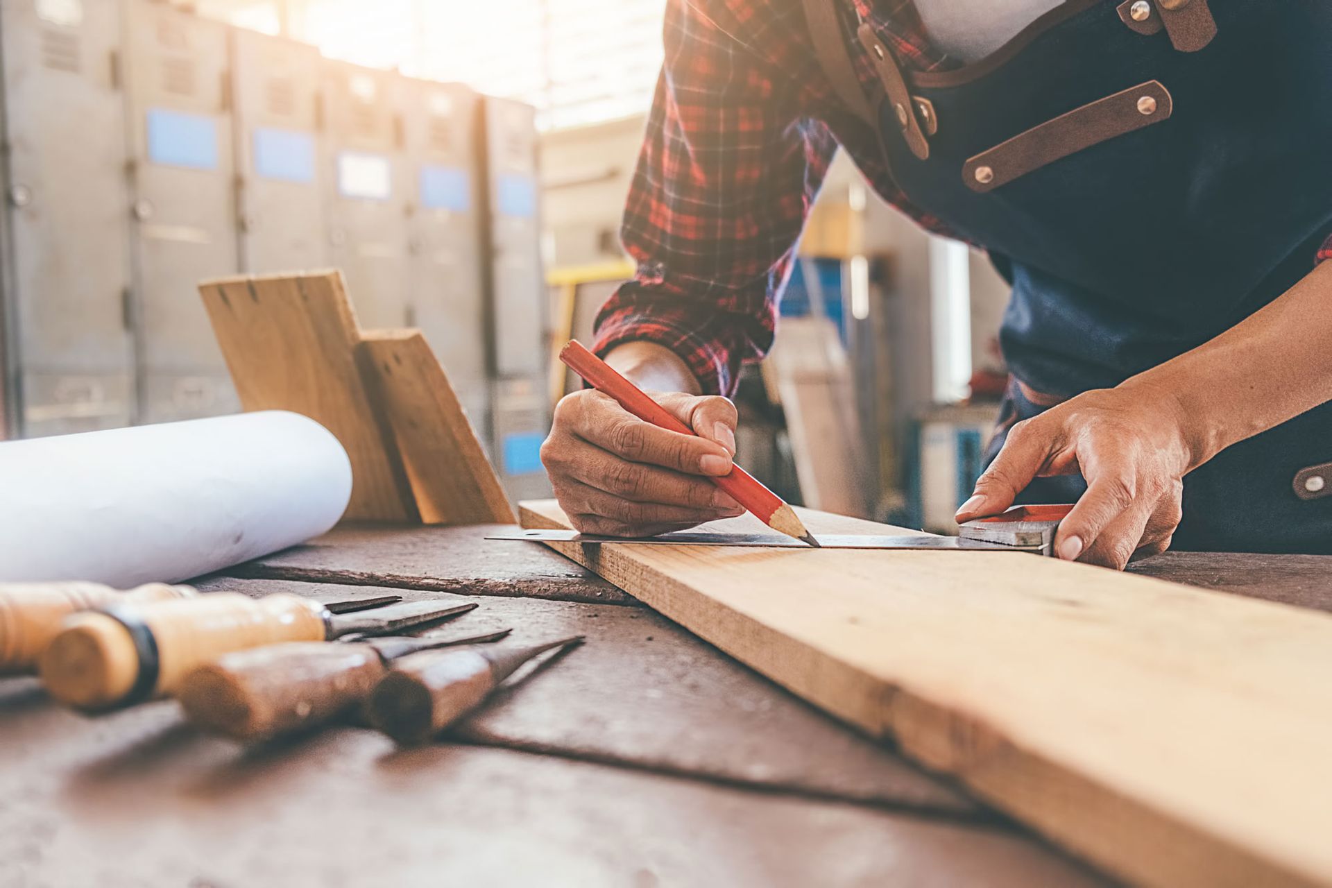 A man is measuring a piece of wood with a ruler.