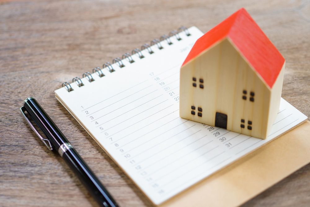 A model house is sitting on top of a notebook next to a pen.