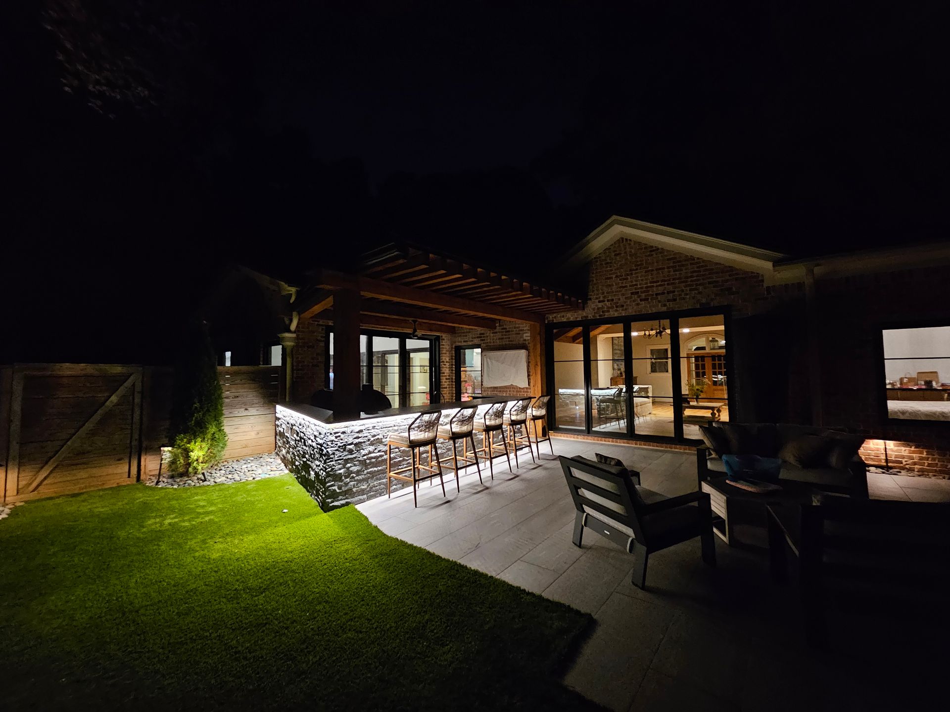 A patio with a bar and chairs is lit up at night.
