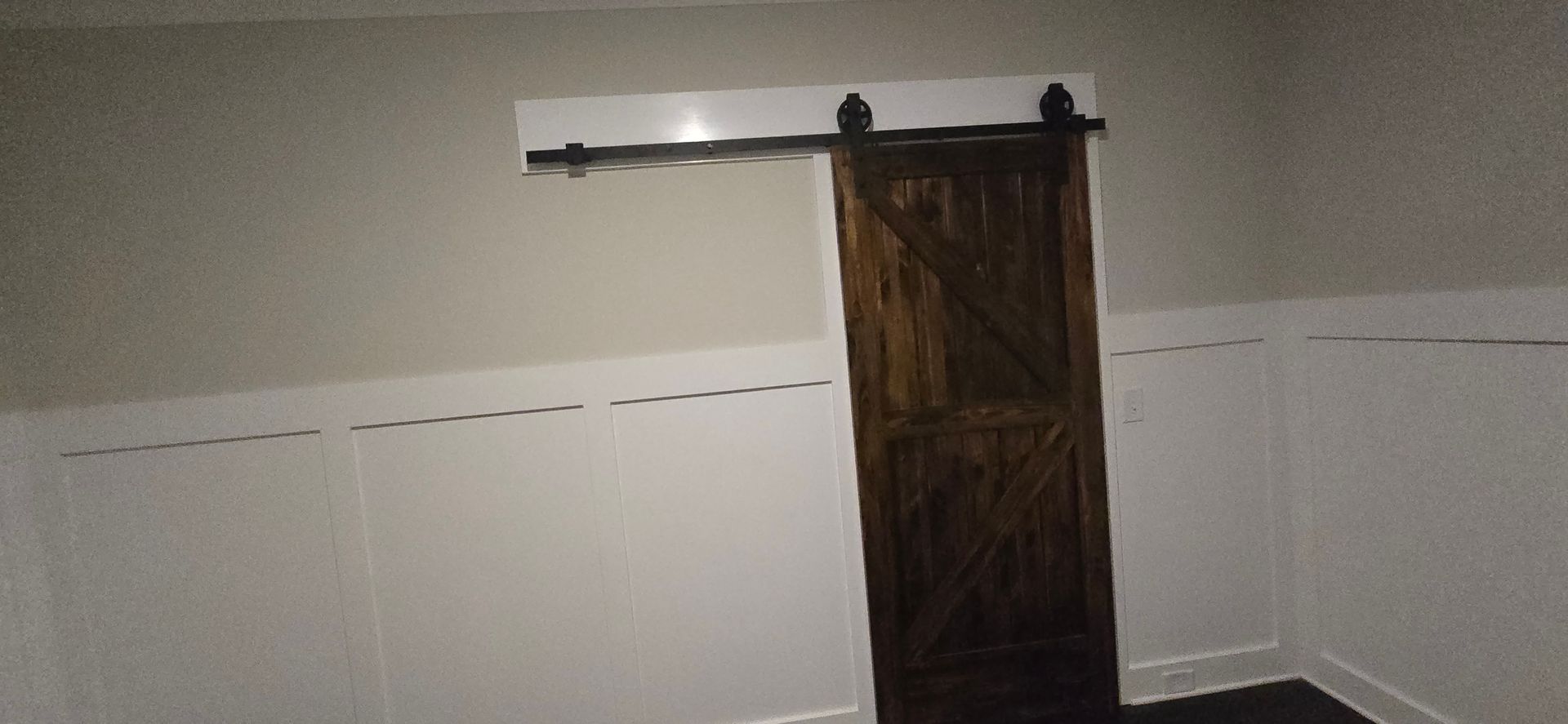 A sliding barn door is in a room with white walls.