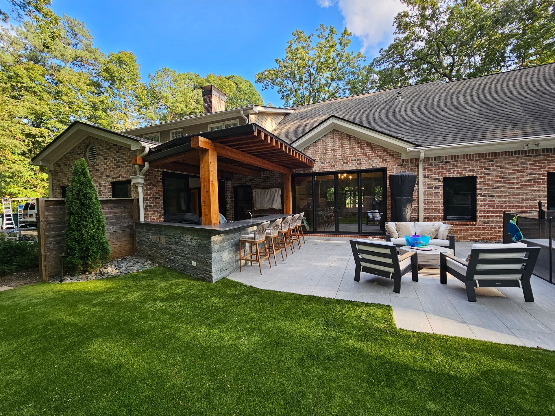 The backyard of a brick house with a patio area and a bar.