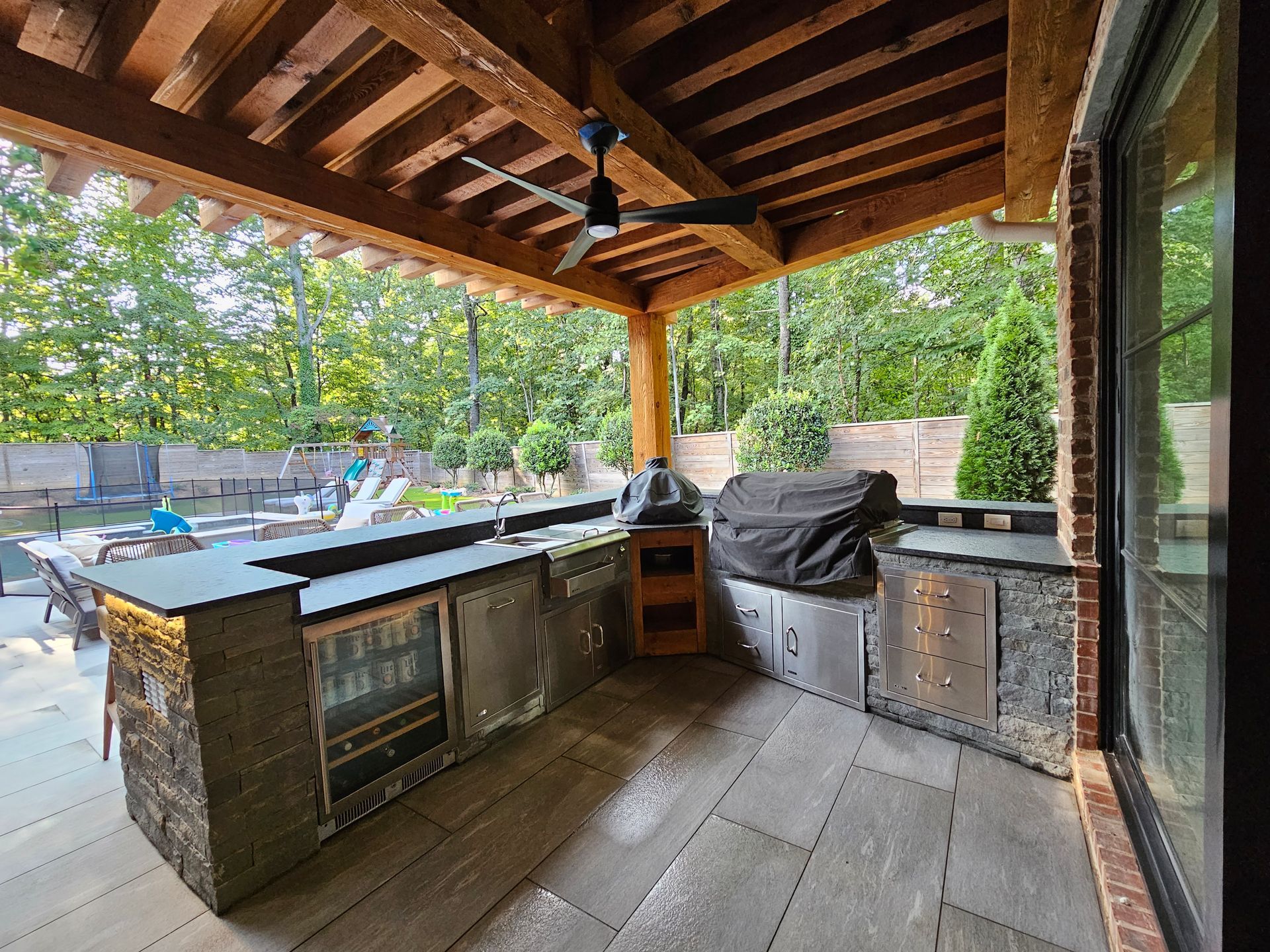 A large outdoor kitchen with a ceiling fan and a sliding glass door.
