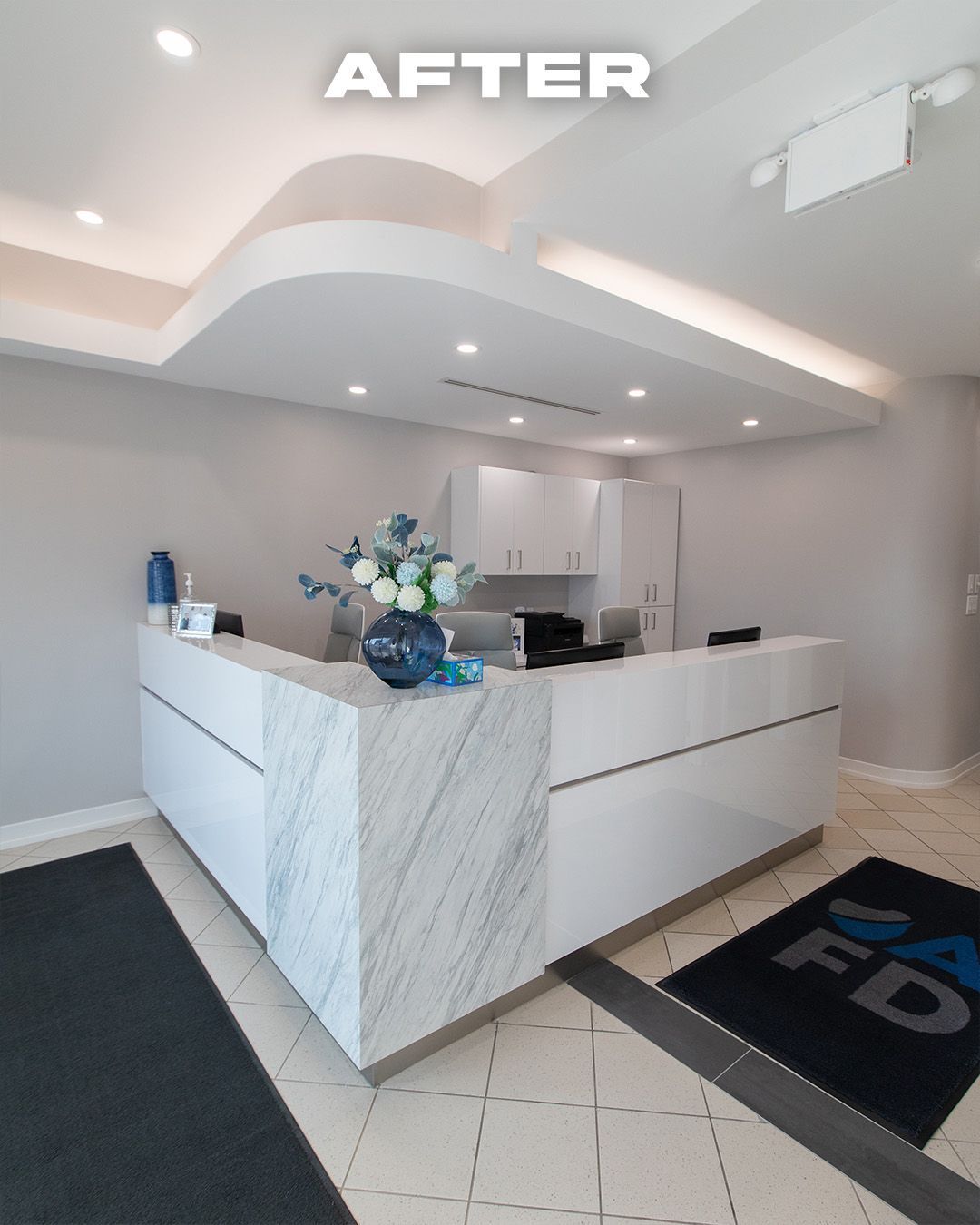 Modern dental office reception area with white marble and cabinetry.