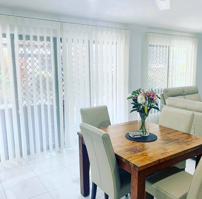 Dining Table With White Vertical Blinds — Window Coverings in Currajong, QLD