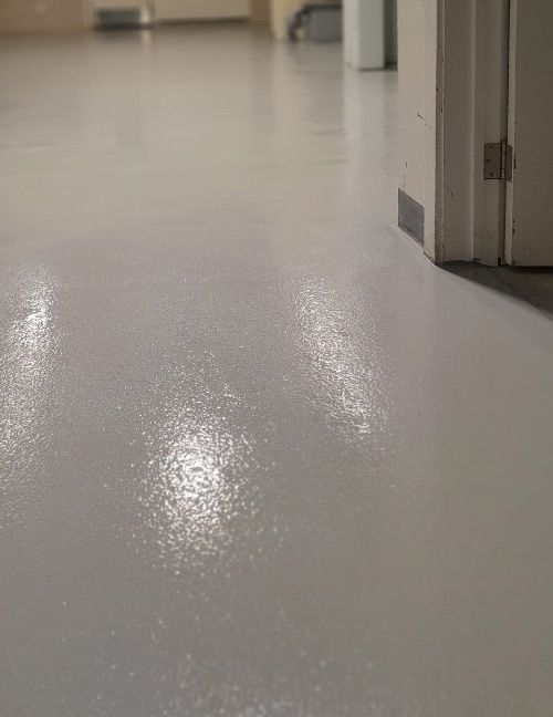 Sol gris brillant recouvert d'époxy avec un cadre de porte en arrière-plan.