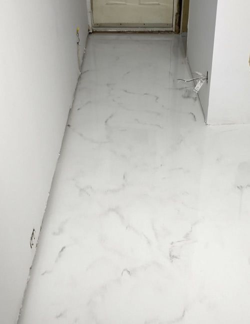 Sol époxy marbré blanc et gris dans le couloir, murs également blancs.