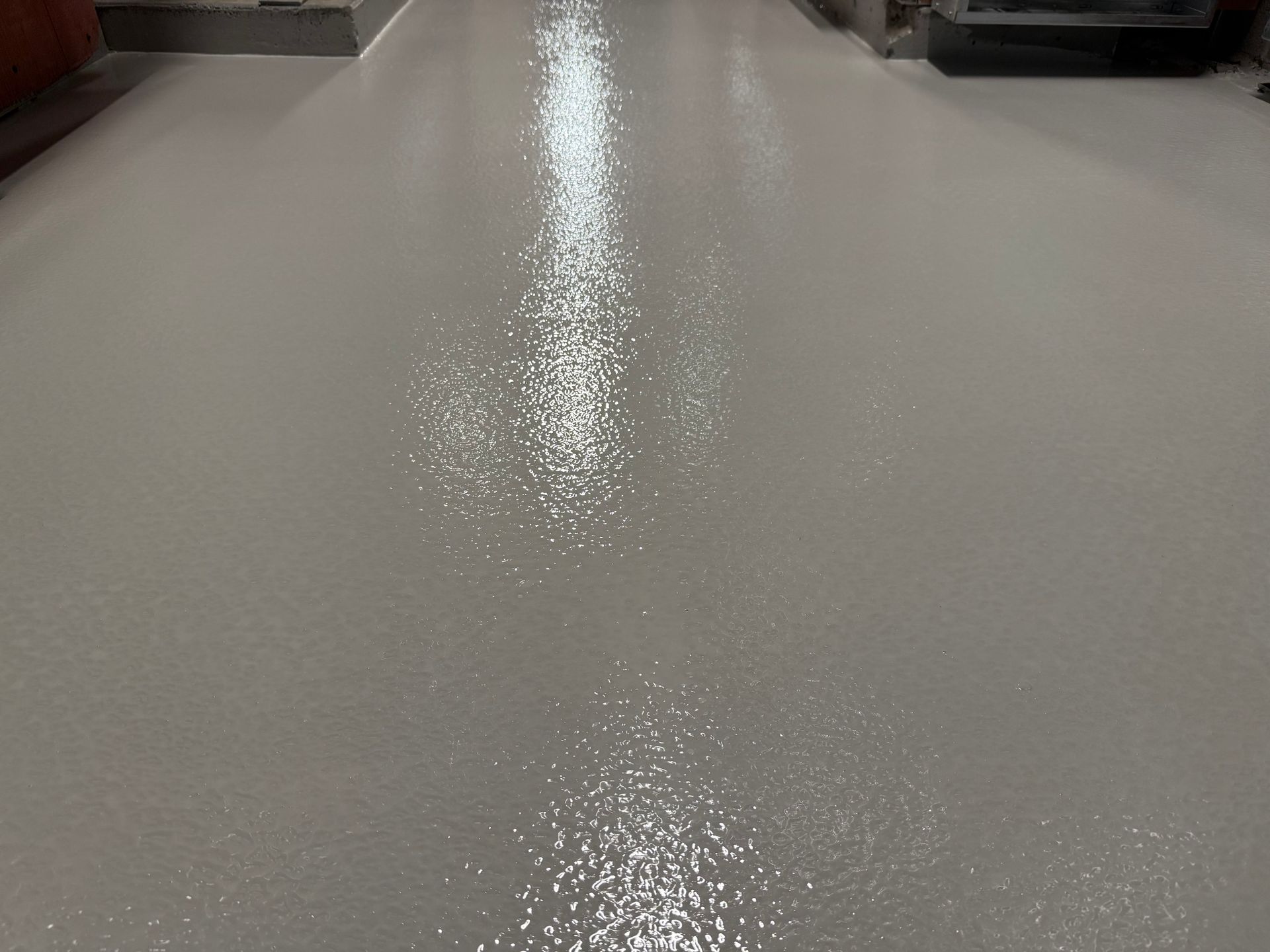 Sol gris brillant reflétant les lumières du plafond dans un environnement industriel.