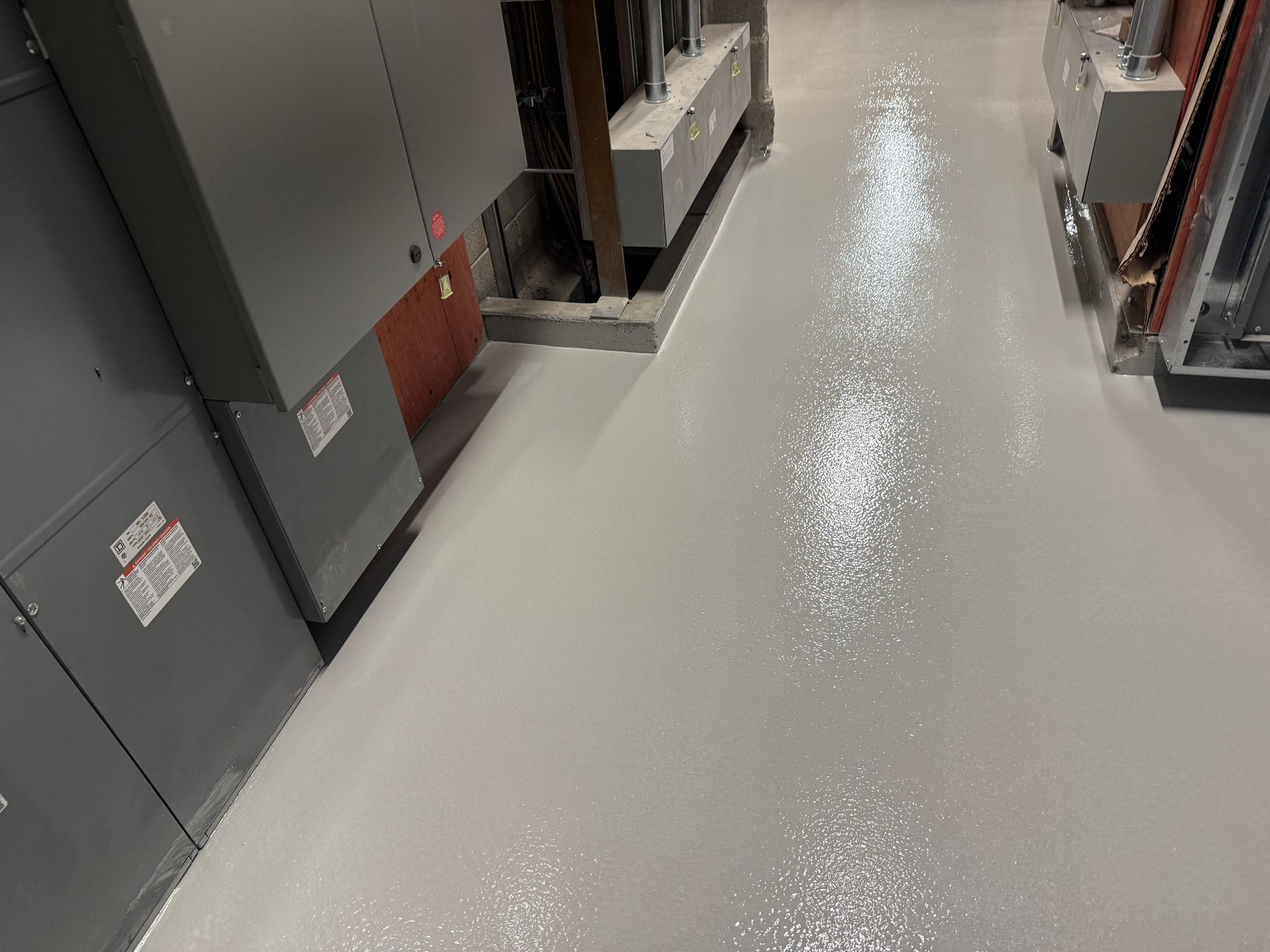 Sol industriel gris avec équipement électrique, partiellement éclairé.