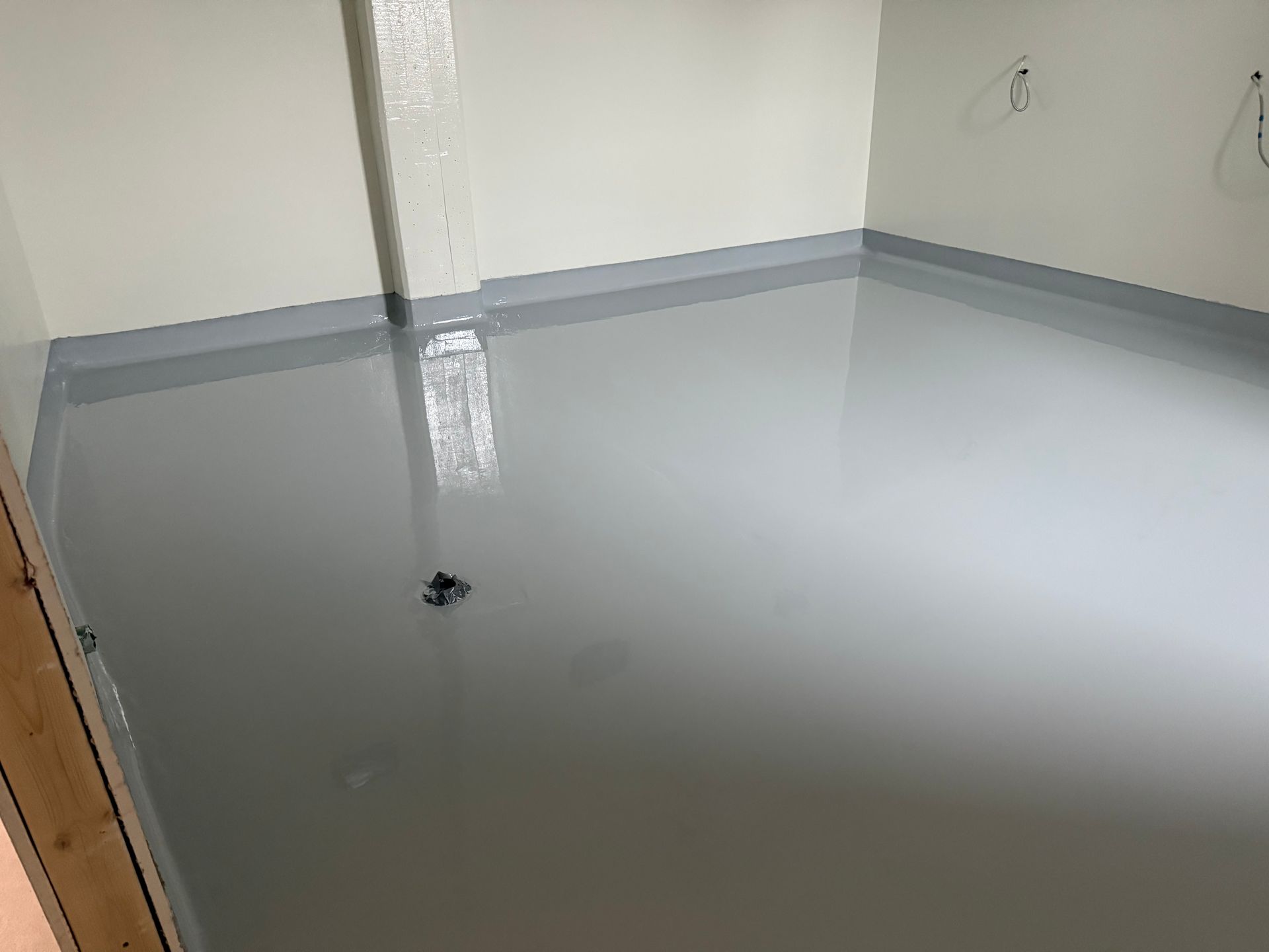 Une pièce avec un sol gris clair brillant, des murs gris clair et une plinthe gris plus foncé.