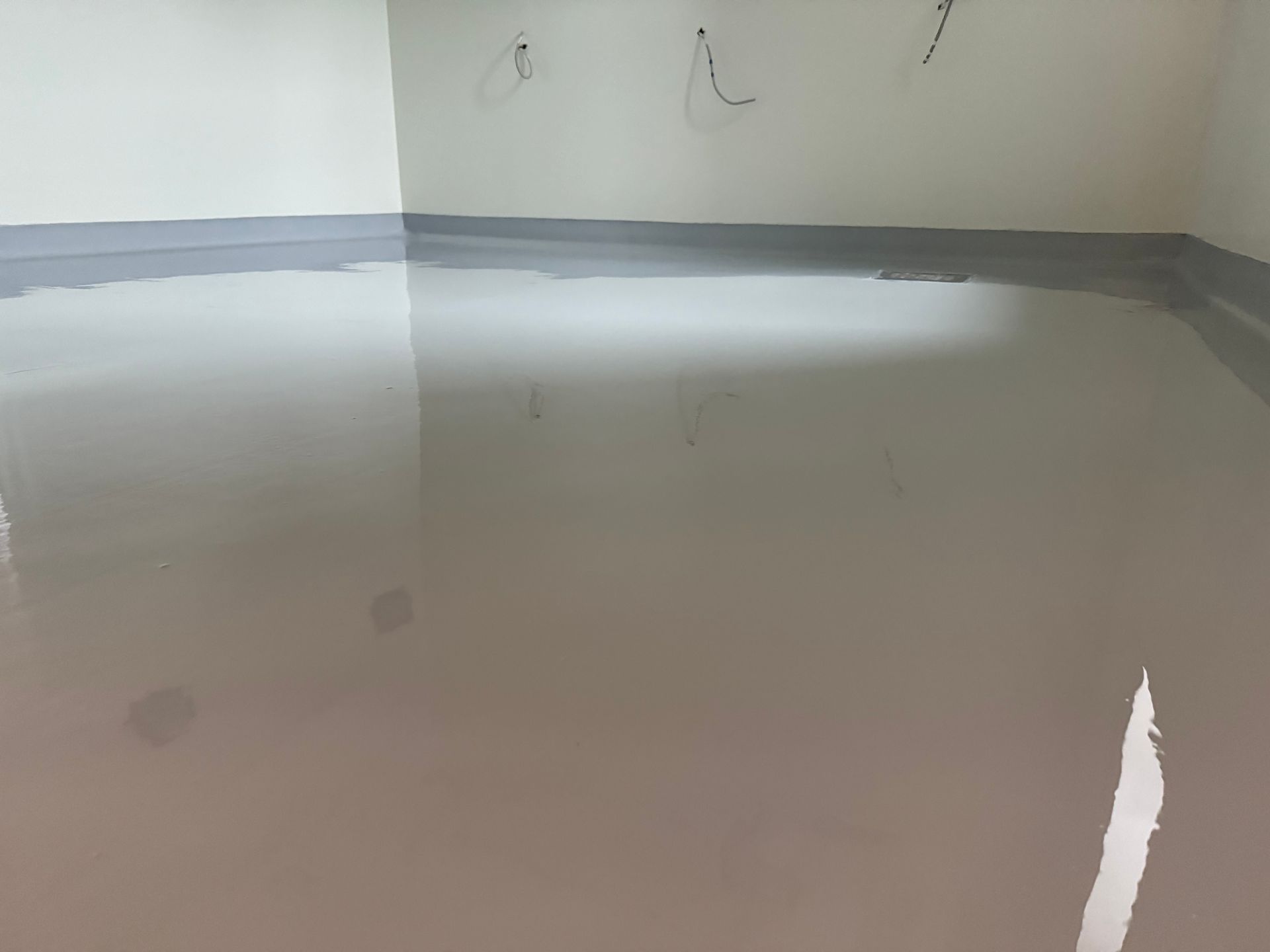 Un sol époxy lisse et gris clair dans une pièce avec des garnitures gris clair et des murs blancs.