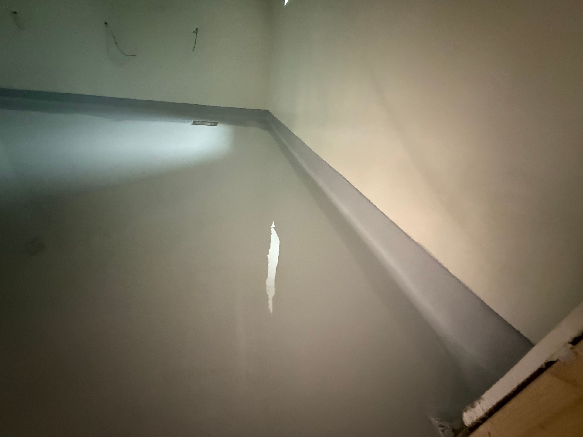 Chambre grise avec une plinthe peinte en gris foncé et une tache blanche sur le mur.