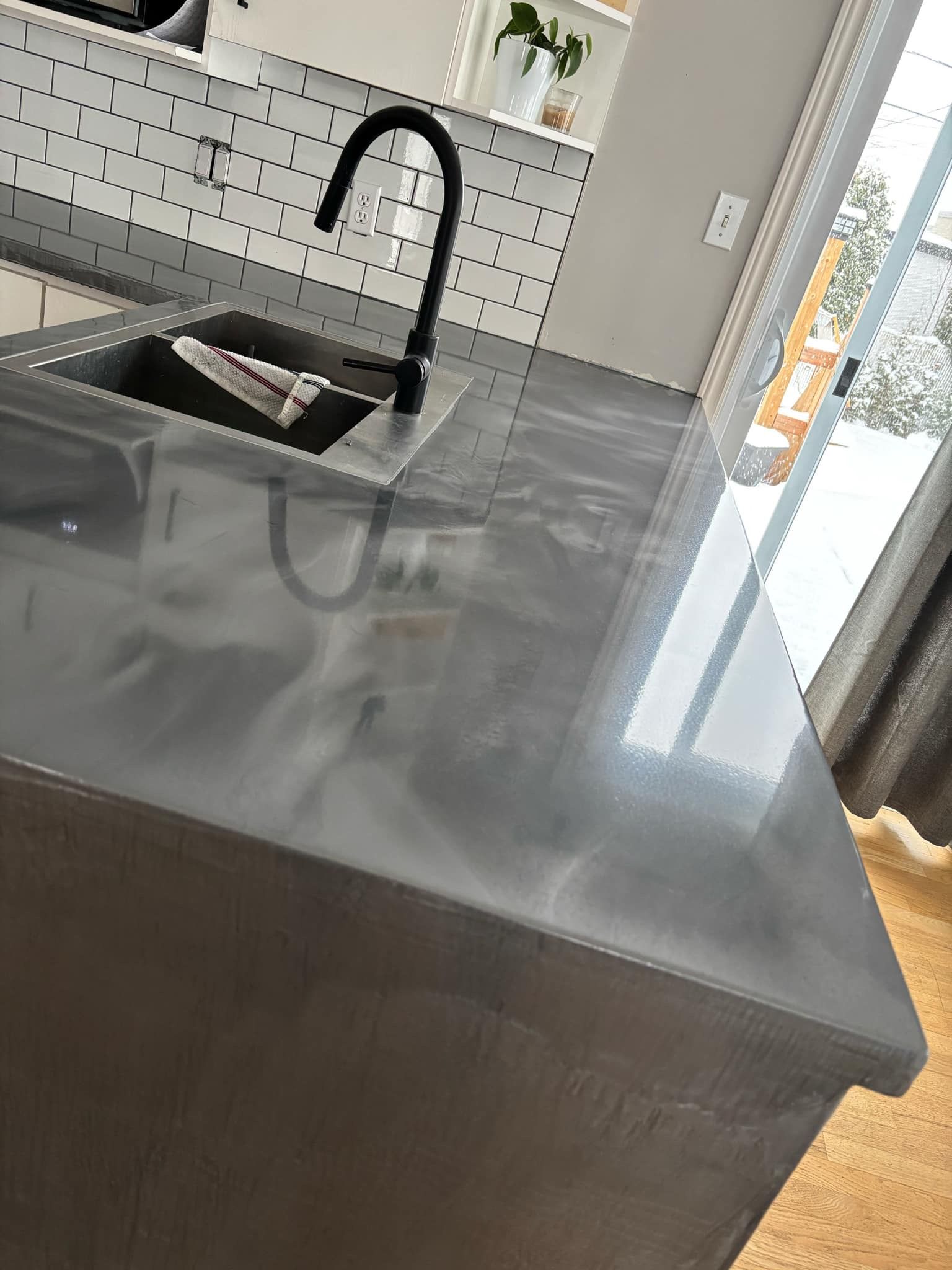 Comptoir de cuisine gris avec un robinet et un évier noirs, probablement dans une cuisine moderne.