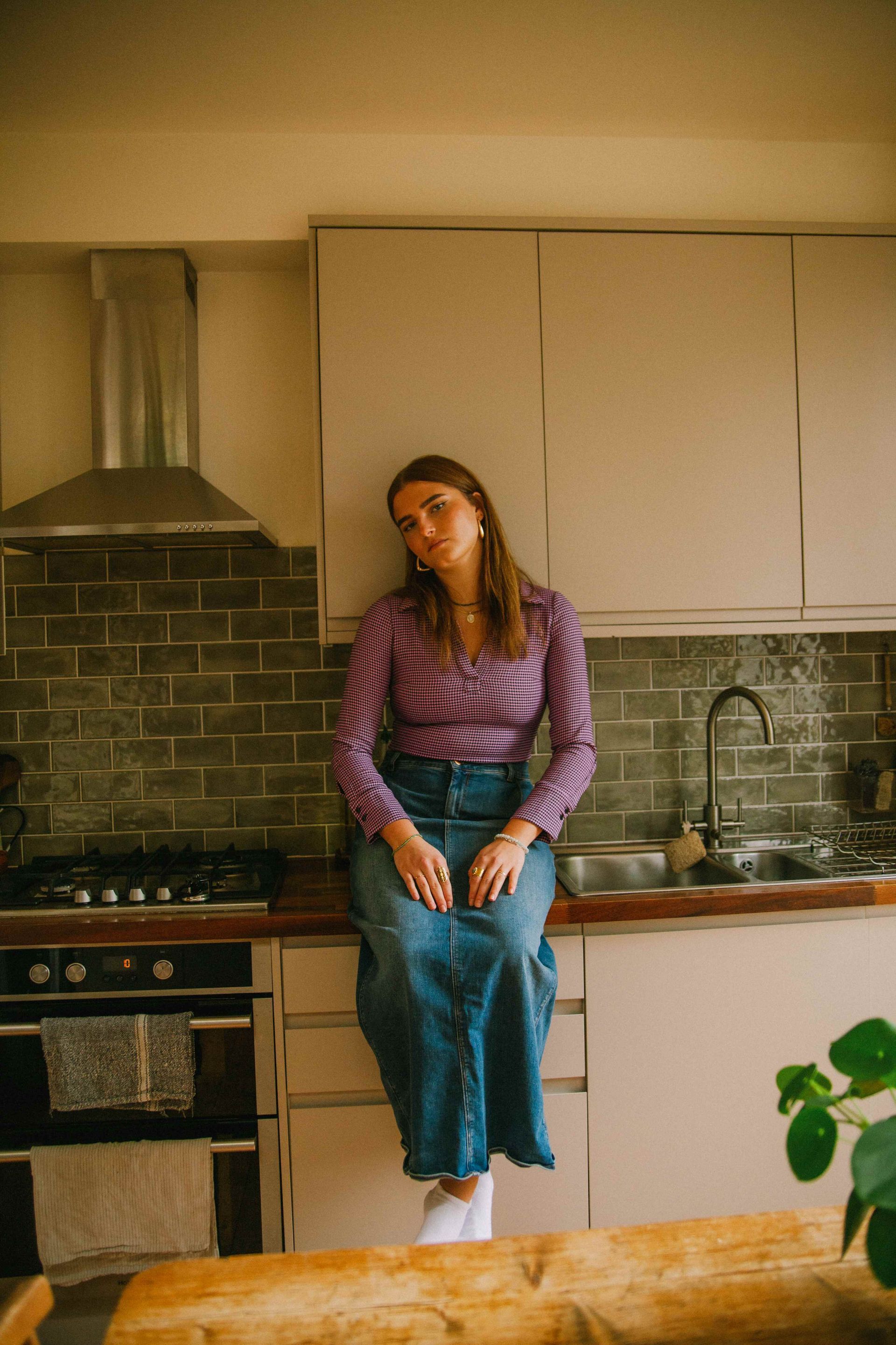 A girl sitting on a countertop by cabinets