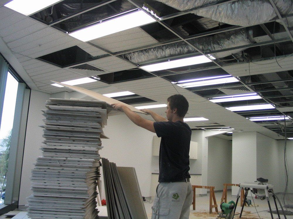 a man is standing in front of a stack of ceiling tiles