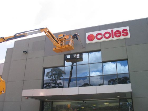 a coles sign is being installed on the side of a building