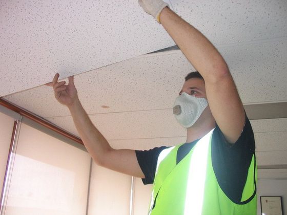 a man wearing a mask is working on a ceiling