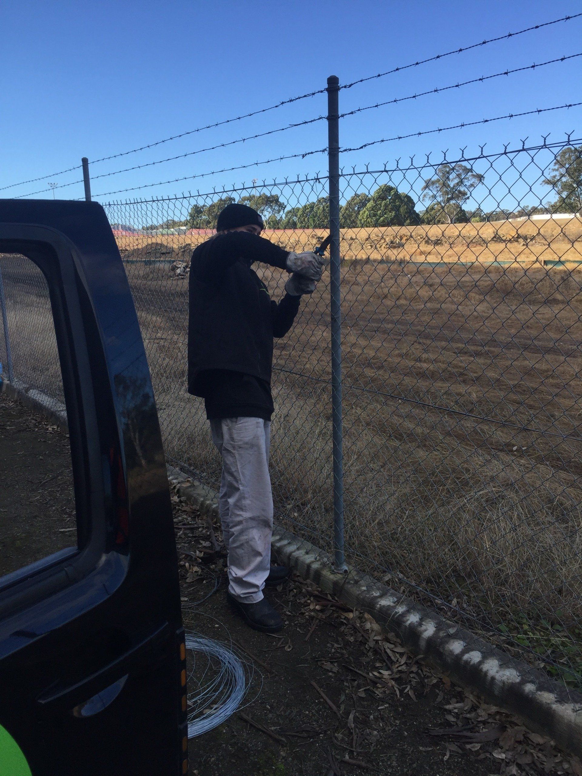 a man is working on a barbed wire fence