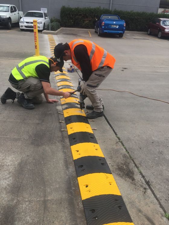 two men are working on a speed bump in a parking lot .