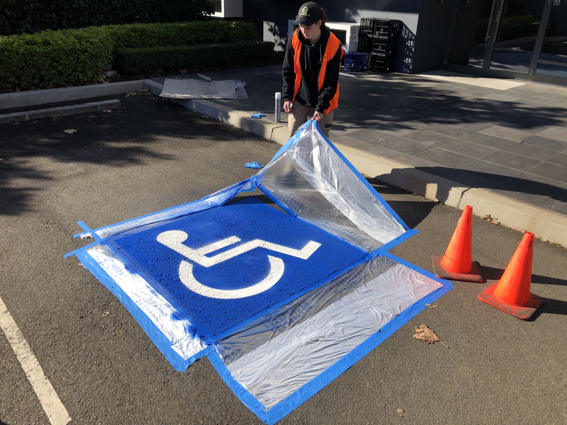 a man is painting a handicap sign in a parking lot .