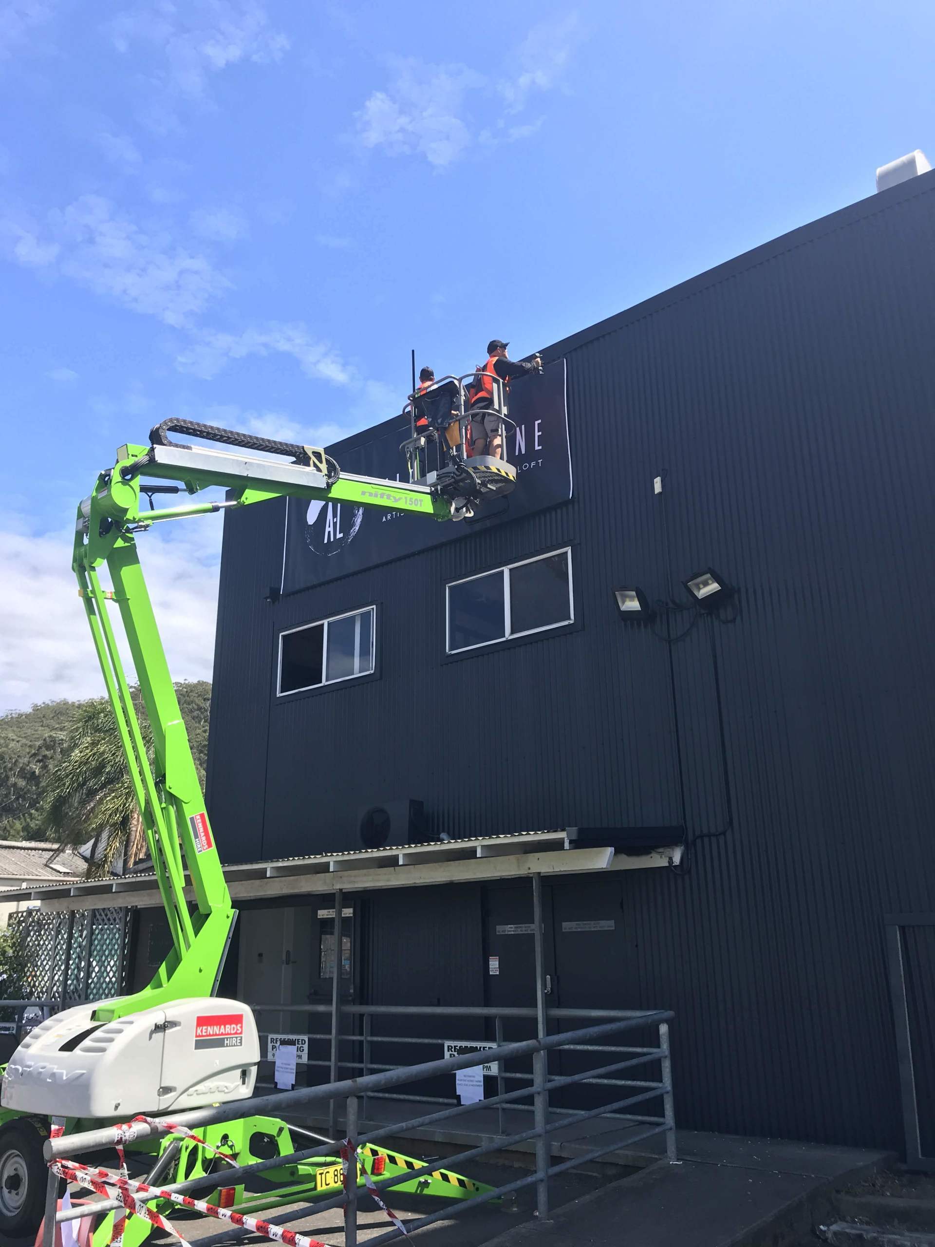 a green crane is being used to paint the side of a building