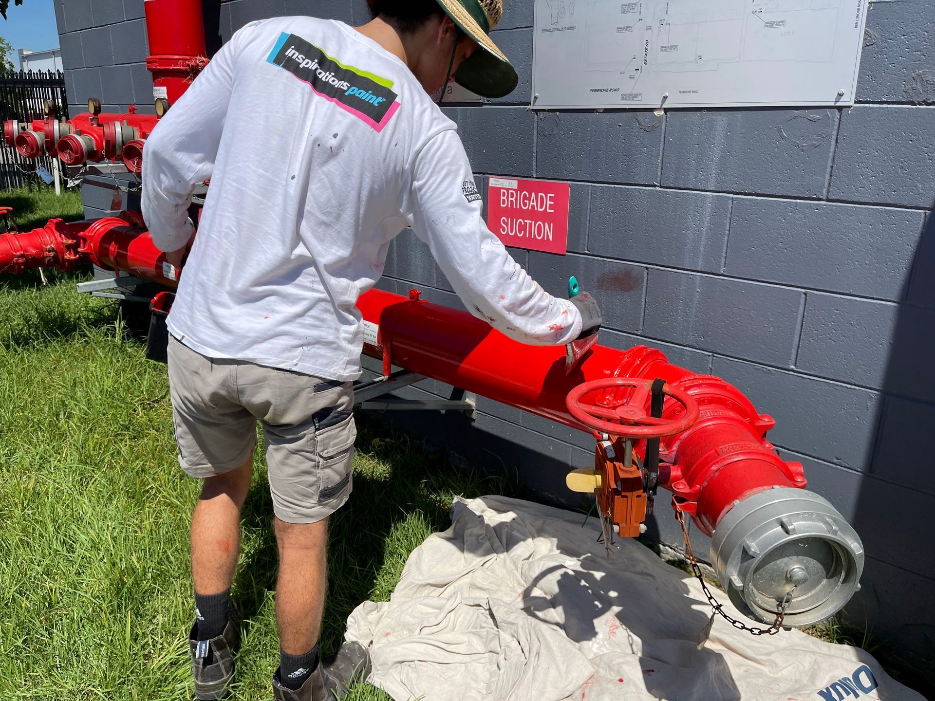 a man in a white shirt is working on a red pipe .