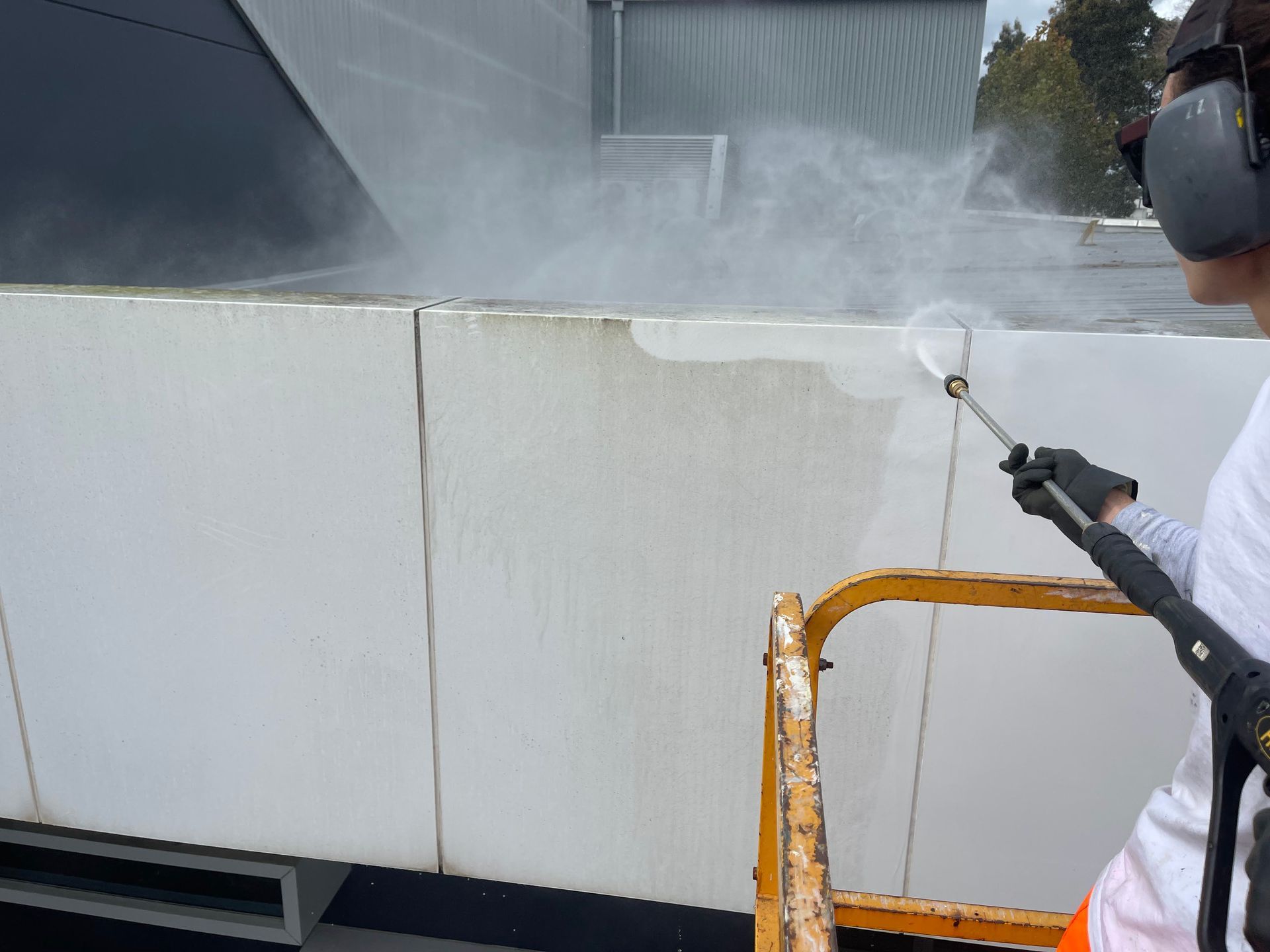 a person is cleaning a wall with a high pressure washer .