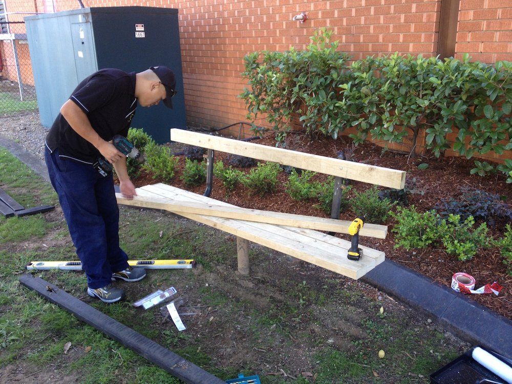 a man is working on a wooden bench in the grass