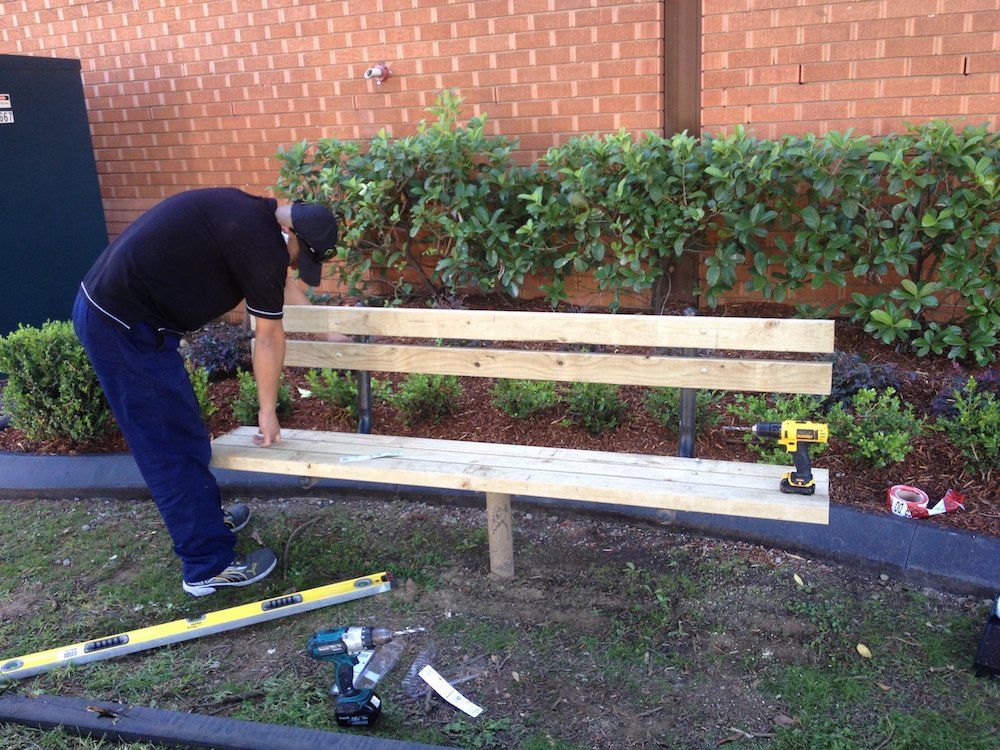 a man is working on a wooden bench in a park
