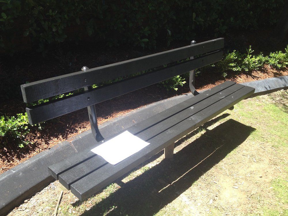 a black park bench with a piece of paper on it