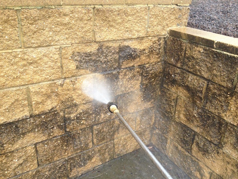 a person is cleaning a brick wall with a high pressure washer .