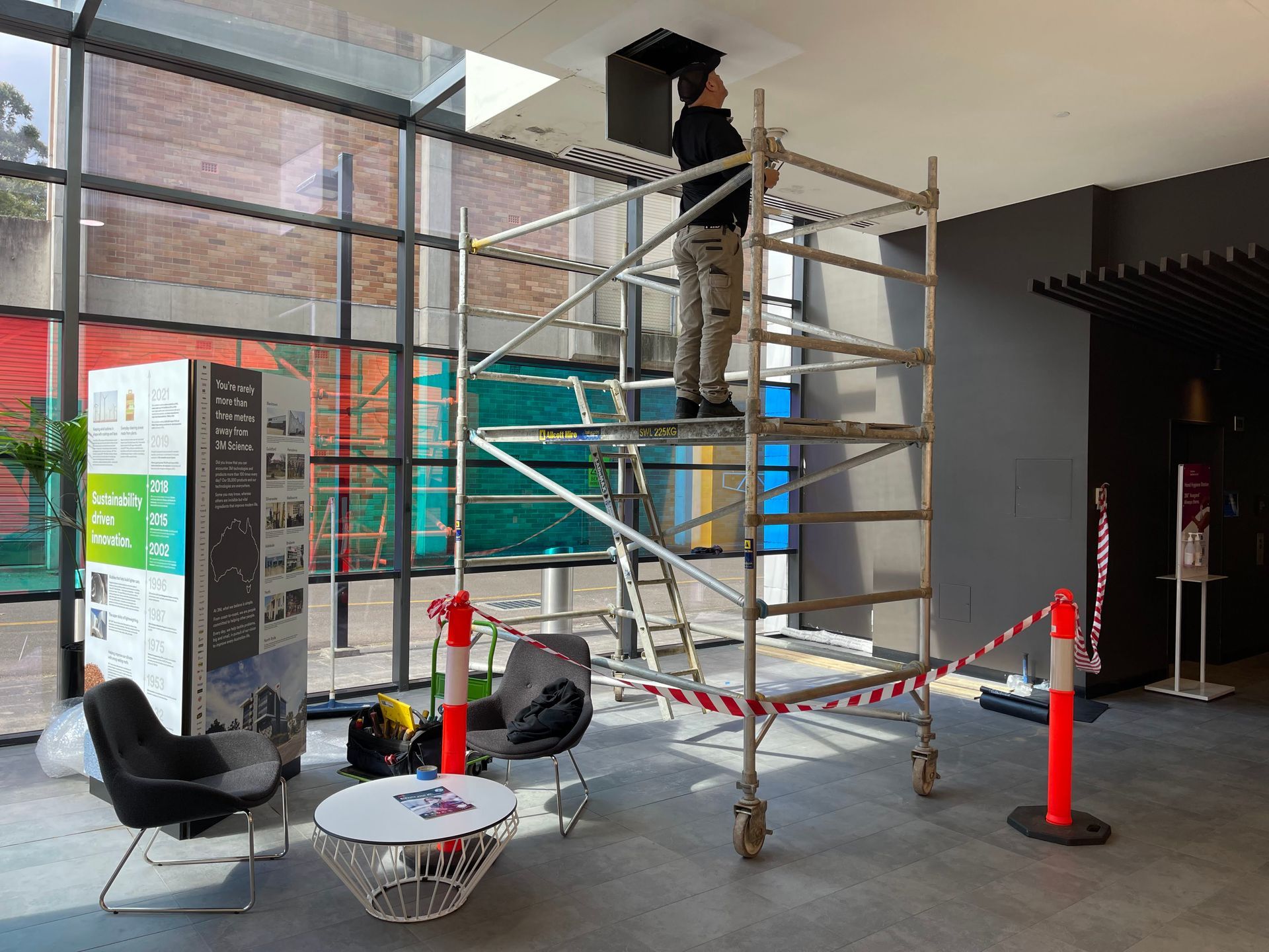 a man is standing on a scaffolding in a lobby .
