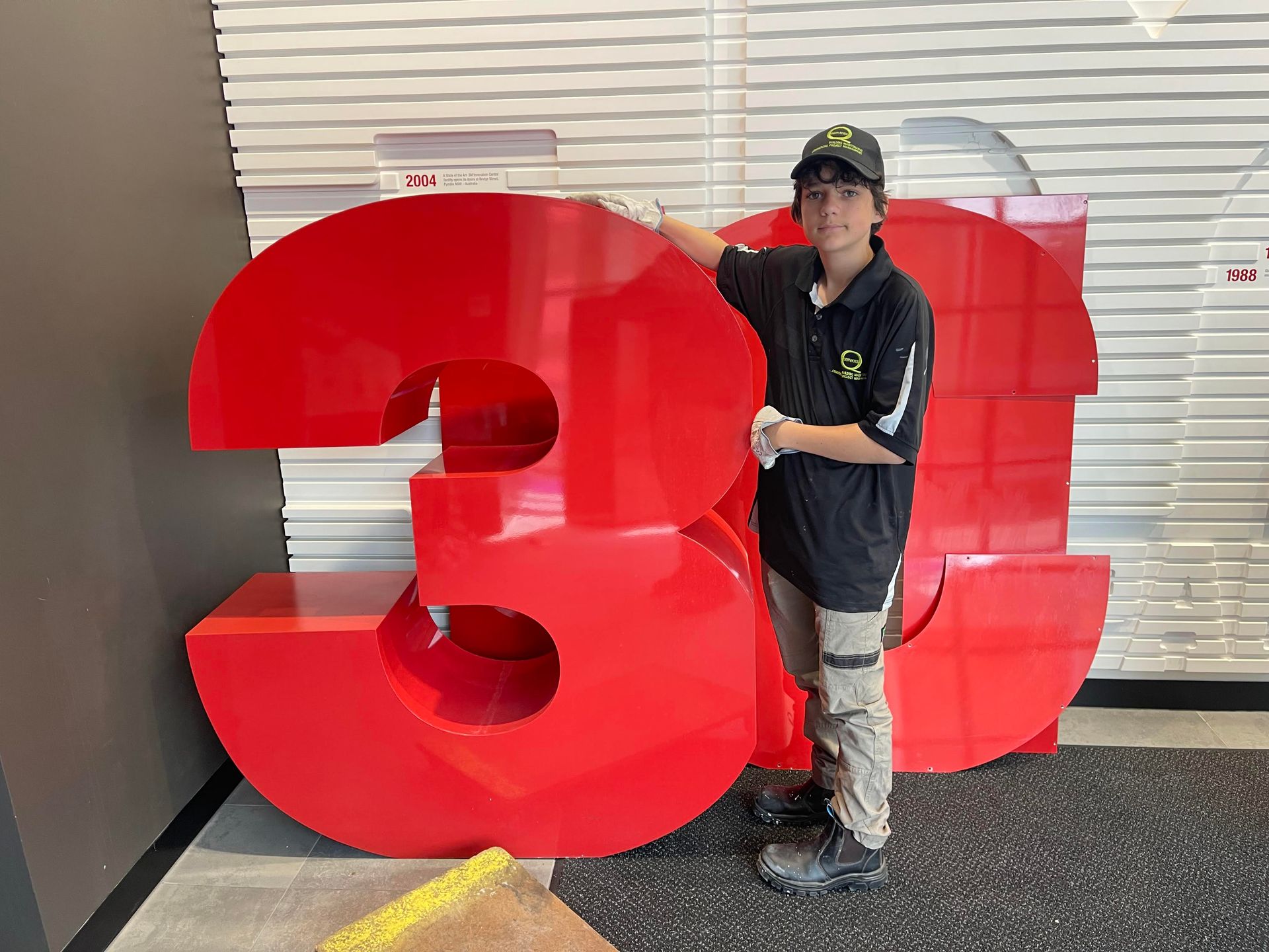 a man is standing in front of a large red 3m sign .