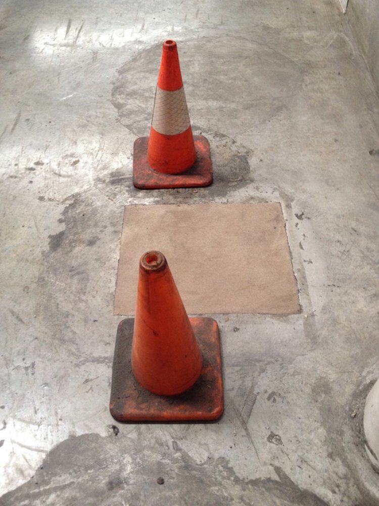 two orange and white traffic cones are sitting on a concrete floor .