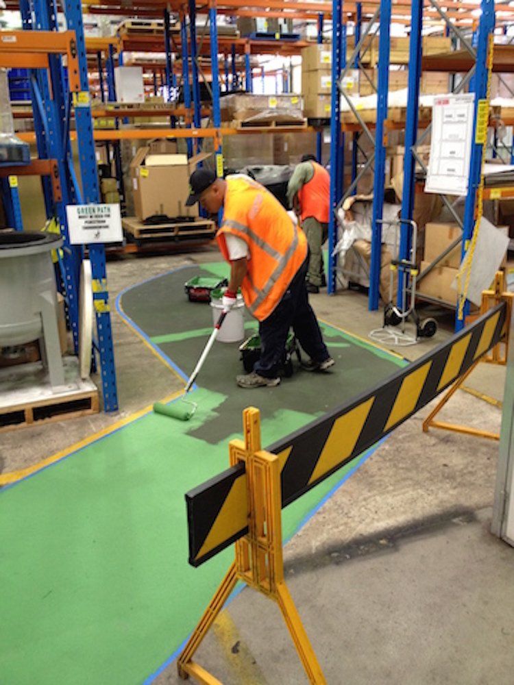 a man is painting a green floor in a warehouse