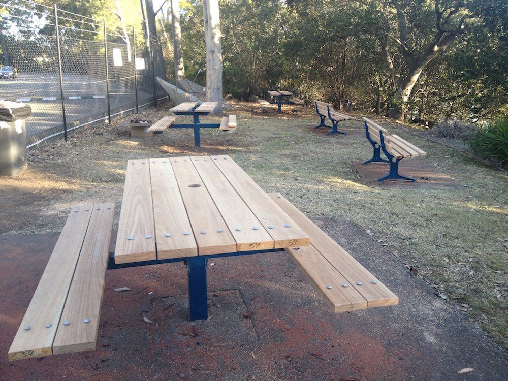 a row of wooden picnic tables and benches in a park