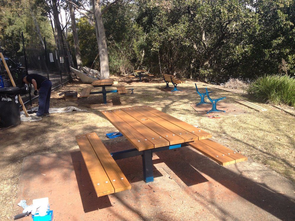 a man is cleaning a picnic table in a park