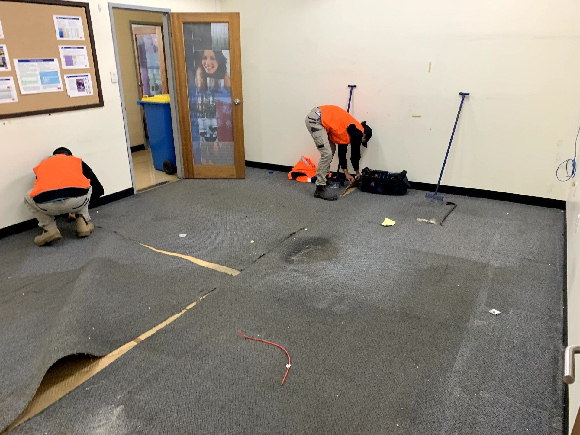 two men are working on a carpeted floor in a room .