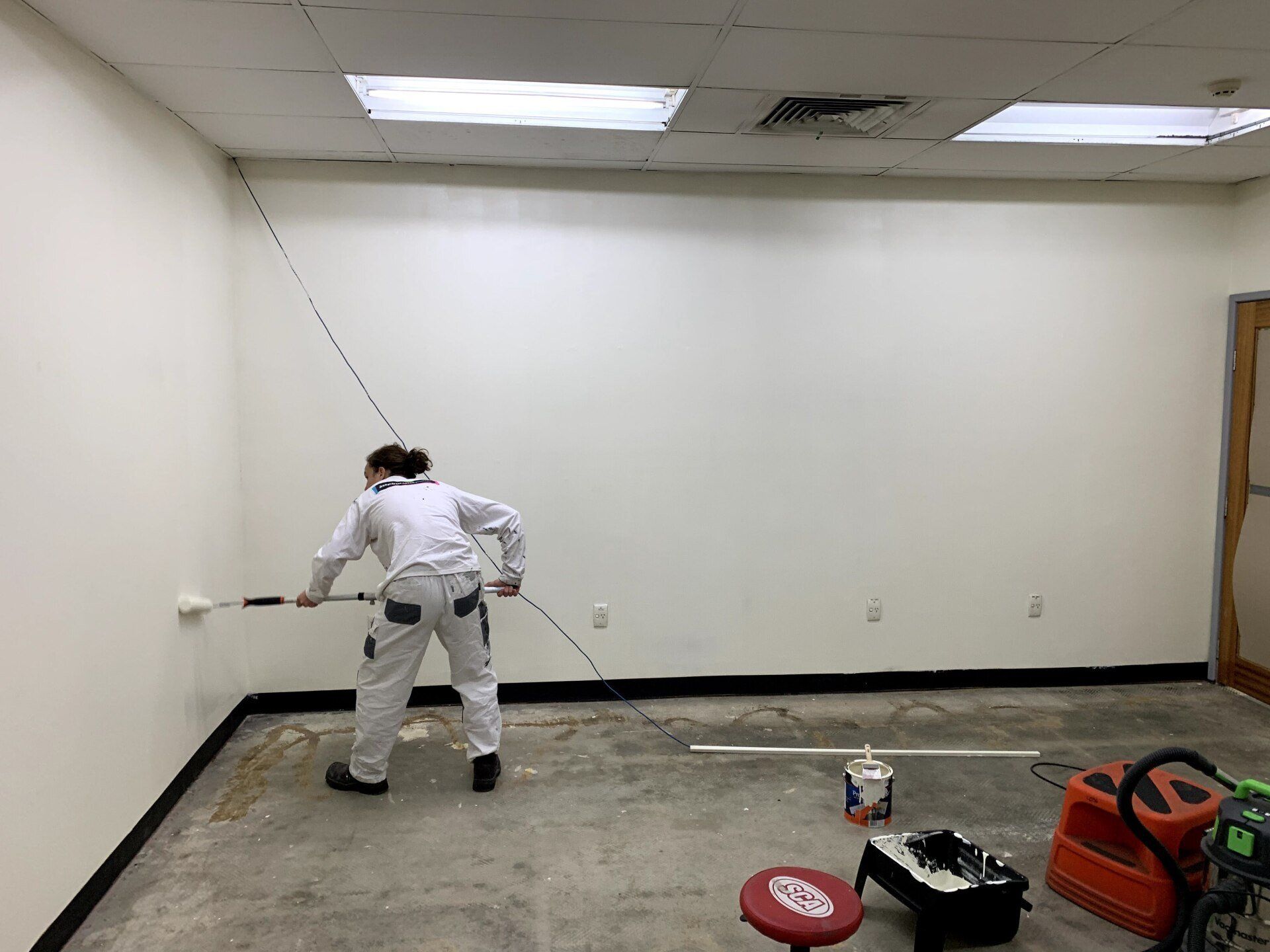 a man is painting a wall in a room with a roller .