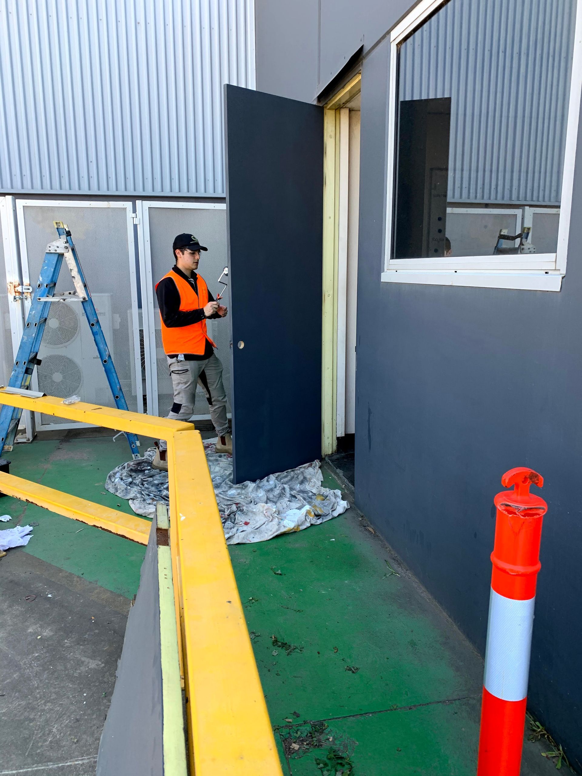 a man is standing in front of a building painting a door .