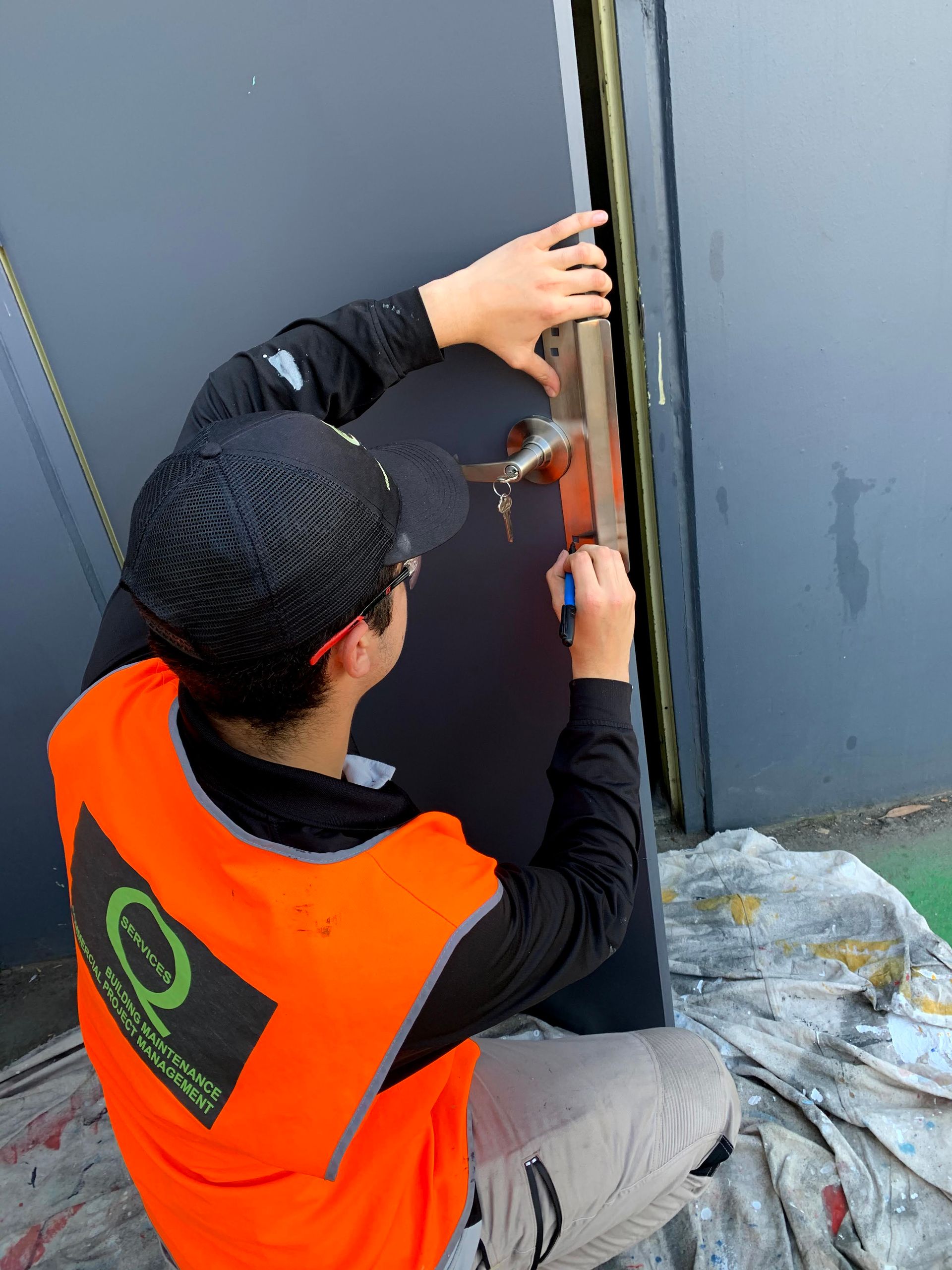 a man in an orange vest is working on a door with a hammer .