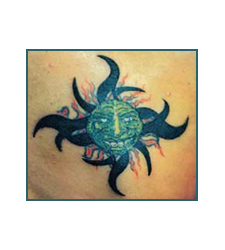 Green-faced sun tattoo with black rays and orange flames.