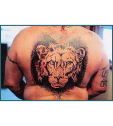 Tattoo of a lion's face on a person's back, black ink, centered composition.