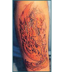 Tattoo of a fiery demon figure engulfed in flames on an arm.