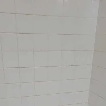 A close up of a white tiled wall in a bathroom.
