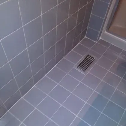 A tiled floor in a bathroom with a drain in the corner.