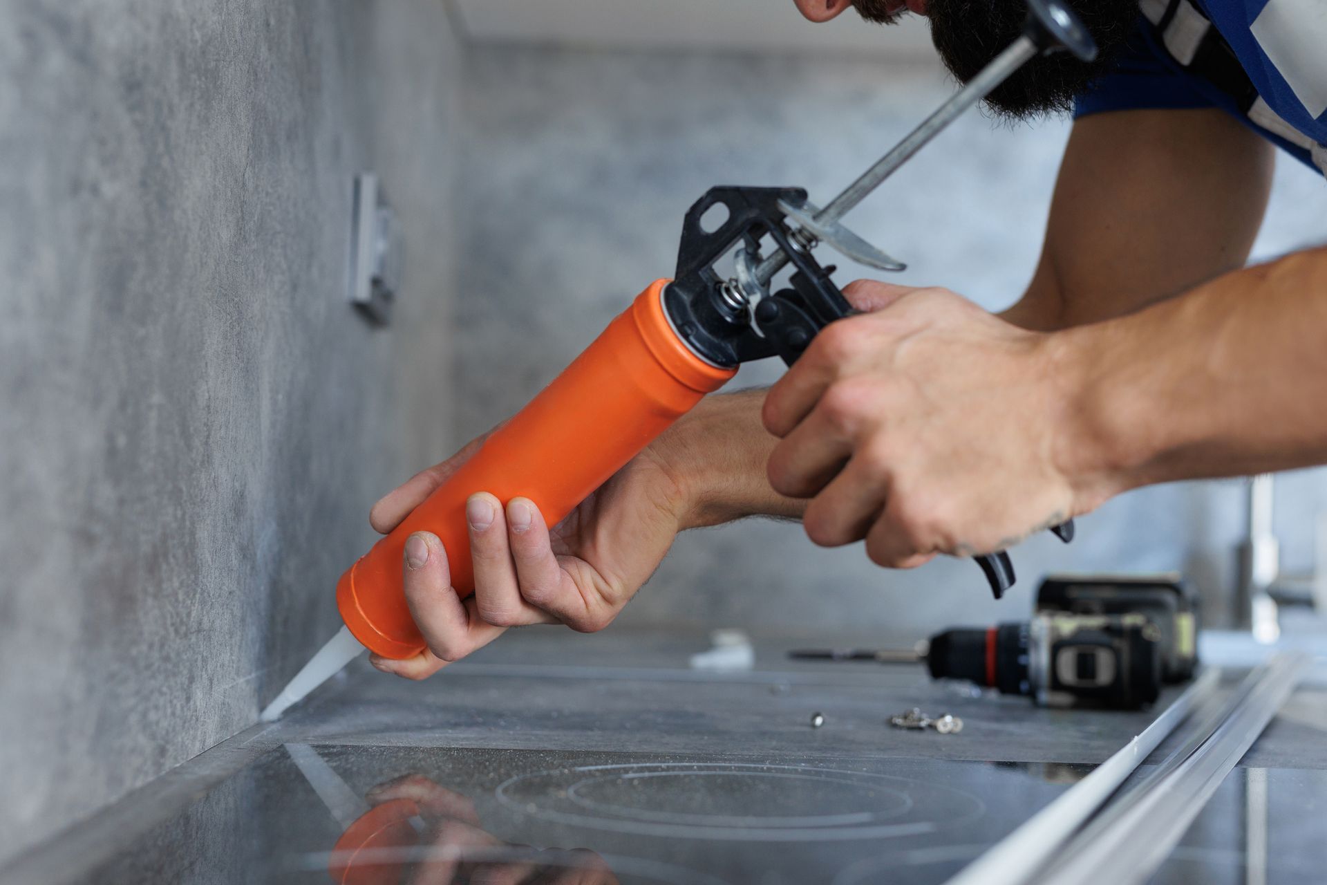 A man is applying silicone to a counter top.